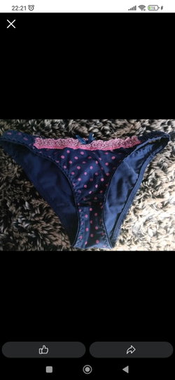 Blue polka-dot thong with pink lace trim laid on a furry gray and white blanket.